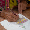 Person coloring a picture with colored pencils on a piece of paper.