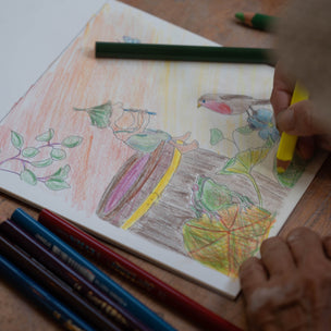 Colorful drawing on paper with colored pencils on a wooden surface