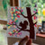 Hand holding a card with a tree and squirrel design in front of a window with greenery outside.