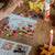 Crafting activity with colorful paper cutouts, glue, and a lit candle on a wooden surface.