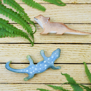 2 wooden lizards on a wooden back drop with ferns