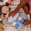 Child playing with a doll on a checkered blanket