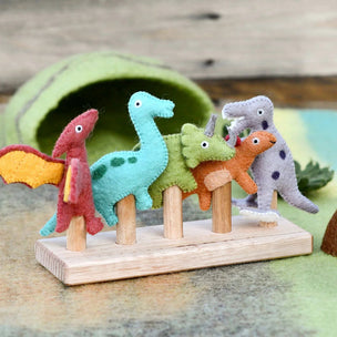 Set of colorful felt dinosaurs on a wooden stand with a wooden background