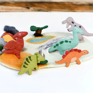 Set of colorful dinosaur toys on a felt landscape with a wooden background