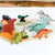 Set of colorful dinosaur toys on a felt landscape with a wooden background