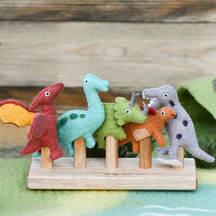 Set of colorful dinosaur toys on a wooden stand with a wooden background