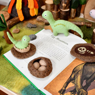 Children's book with dinosaur figures and a campfire scene