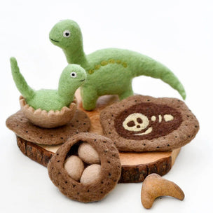 Felted dinosaur toys with wooden nests and bones on a white background