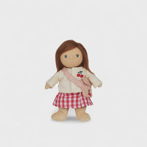 Doll wearing a cream jacket with cherry design, red checkered skirt, and pink bag on a white background