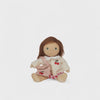 Small doll with brown hair and a pink outfit on a white background