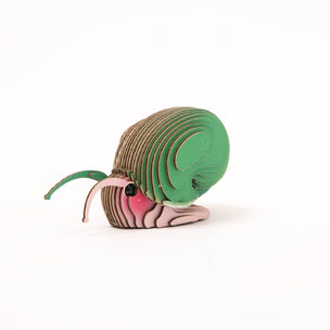 A 3D cardboard DIY model of a snail, constructed with layered wooden slats, featuring a brown body, green head and ear, and pink and white stripes on the face, set against a plain white background.