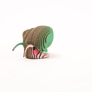 A 3D cardboard DIY model of a snail, constructed with layered wooden slats, featuring a brown body, green head and ear, and pink and white stripes on the face, set against a plain white background.