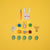 Set of wooden toys including a rabbit head, carrots, turtles, and leaves on a yellow background