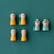 Five small wooden toy figures with cat faces are arranged on a teal background. Four figures are yellow, and two are light blue.