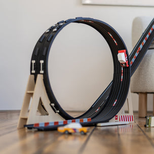 Toy car track set up with a circular track and small cars on a wooden floor.