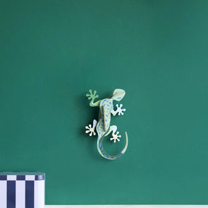 Decorative lizard wall art on a green wall with a striped box at the bottom.