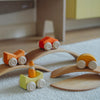 Wooden toy cars on a track set on a light-colored surface
