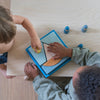 Child and adult interacting with a toy on a wooden floor