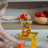 Child playing with wooden building blocks on a light-colored rug.