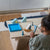 Child playing with toys on a wooden table in a minimalistic room.