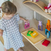 Child playing with colorful toys on a wooden shelf