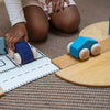 Child playing with toy cars on a wooden track and paper road map.