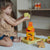 Child playing with colorful wooden toys on a carpeted floor.