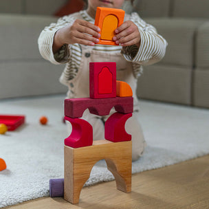Child playing with colorful wooden blocks on a light-colored rug.
