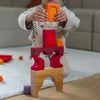 Child playing with colorful wooden blocks on a light-colored rug.