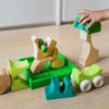 Child playing with wooden toy blocks on a light wood floor.