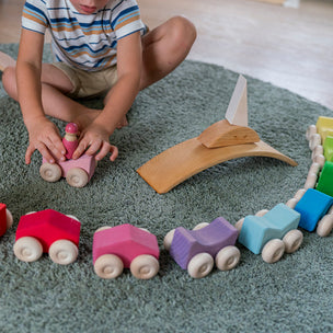 Child playing with a wooden toy train set on a rug
