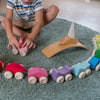 Child playing with a wooden toy train set on a rug