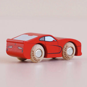Red toy car with wooden wheels on a light pink background