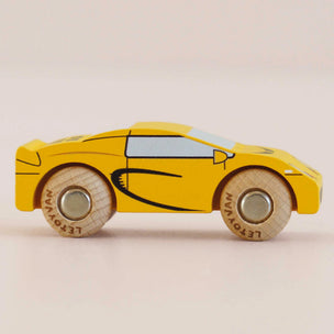 Yellow toy car with wooden wheels on a beige background