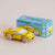 Yellow toy car next to its packaging box on a beige background