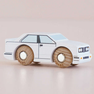White toy car with wooden wheels on a beige background