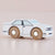 White toy car with wooden wheels on a beige background