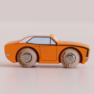 An orange wooden toy car with hand-painted details, including a light blue roof window, black outlines, and natural wood wheels with 'LEGOYAM' lettering, shown on a neutral beige background.