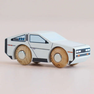 Wooden toy car with a white body and wooden wheels on a beige background