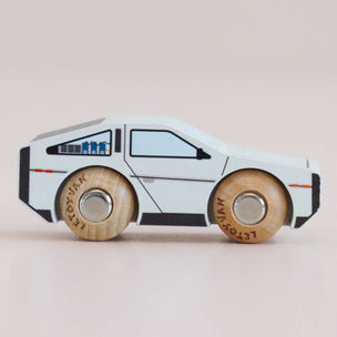 Wooden toy car with a white body and brown wheels on a beige background