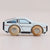Wooden toy car with a white body and brown wheels on a beige background