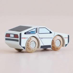 Wooden toy car with a white body and wooden wheels on a beige background