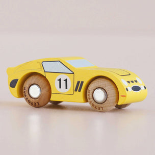 Yellow toy car with wooden wheels on a light beige background