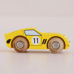 Yellow toy car with wooden wheels on a light background
