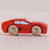 Red toy car with wooden wheels on a light pink background