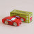 Red toy car next to its packaging box on a beige background