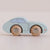 A light blue wooden toy car with natural wood wheels, photographed on a plain beige background.