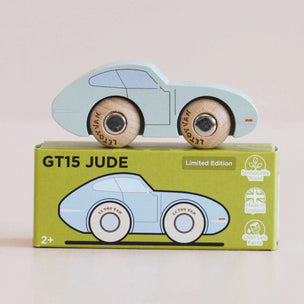 A light blue wooden toy car with natural wood wheels sits on top of its green 'GT15 JUDE Limited Edition' packaging box against a soft beige background.