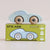 A light blue wooden toy car with natural wood wheels sits on top of its green 'GT15 JUDE Limited Edition' packaging box against a soft beige background.
