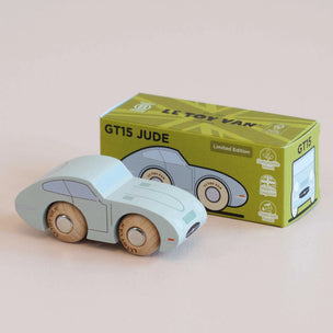 A wooden toy car in a pale mint green color with natural wood wheels, shown next to its green and yellow 'Le Toy Van' GT15 Jude limited edition packaging box on a light beige background.